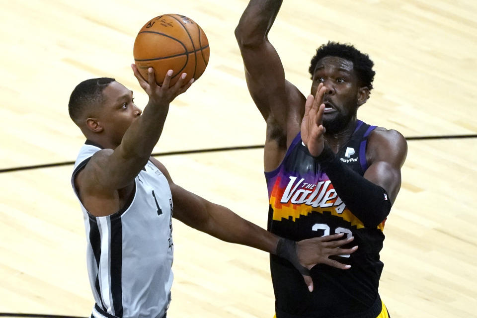 San Antonio Spurs guard Lonnie Walker IV (1) shoots next to Phoenix Suns center Deandre Ayton during the first half of an NBA basketball game Saturday, April 17, 2021, in Phoenix. (AP Photo/Rick Scuteri)