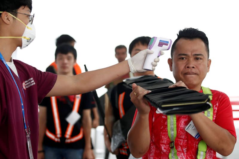 Workers have their temperatures taken at the arrival area during a media preview of the Singapore Airshow in Singapore