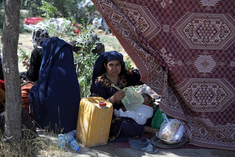 In this Aug. 9, 2021 file photo, an internally displaced Afghan woman from a northern province, who fled her home due to fighting between the Taliban and Afghan security personnel, fans her sleeping child, in a public park in Kabul, Afghanistan.