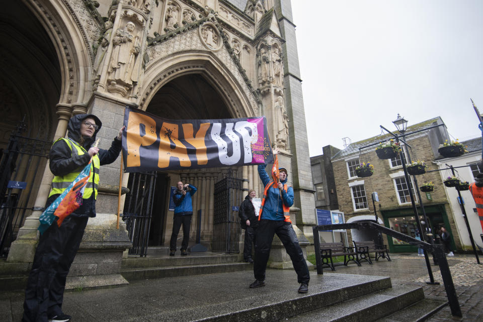 TRURO, CORNWALL, UNITED KINGDOM - 2023/03/16: Protesters hold a banner that says Pay up outside the Truro Cathedral during the demonstration. Teachers and members from the National Education Union (NEU) gathered in the city during a day of national strike in dispute of salary increase with the government. (Photo by Benjamin Gilbert/SOPA Images/LightRocket via Getty Images)