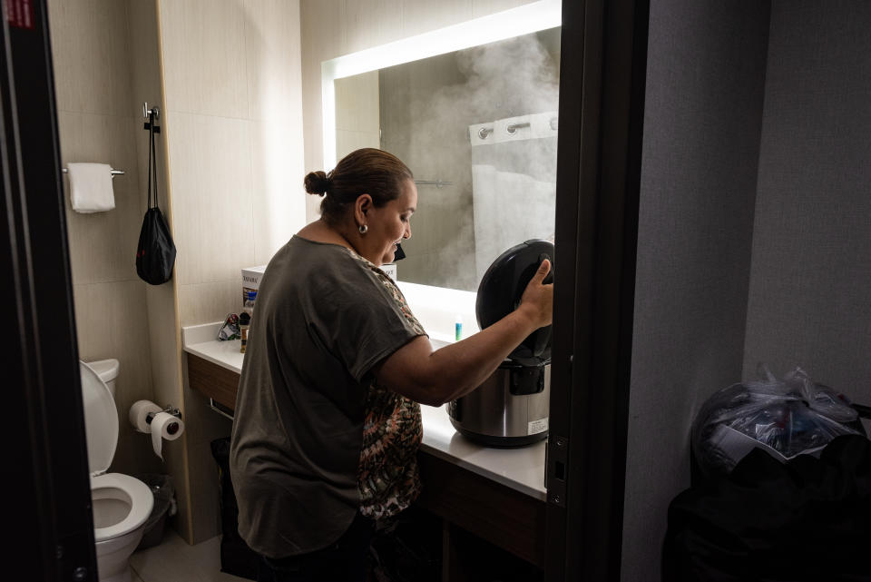 <span class="s1">Jenyffer Ortiz cooks chicken in a rice cooker in the hotel bathroom, where there is counter space. She cooks for herself to better deal with diabetes and other ailments. (Photo: David “Dee” Delgado for Yahoo News)</span>