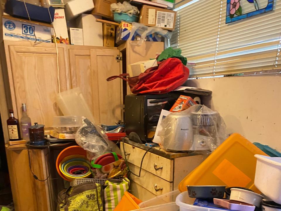 A room with cabinets piled high with assorted boxes, bins, and trash.