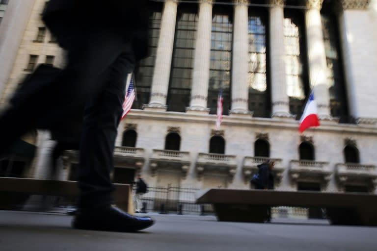 People walk outside of the New York Stock Exchange (NYSE) during morning trading on November 23, 2015