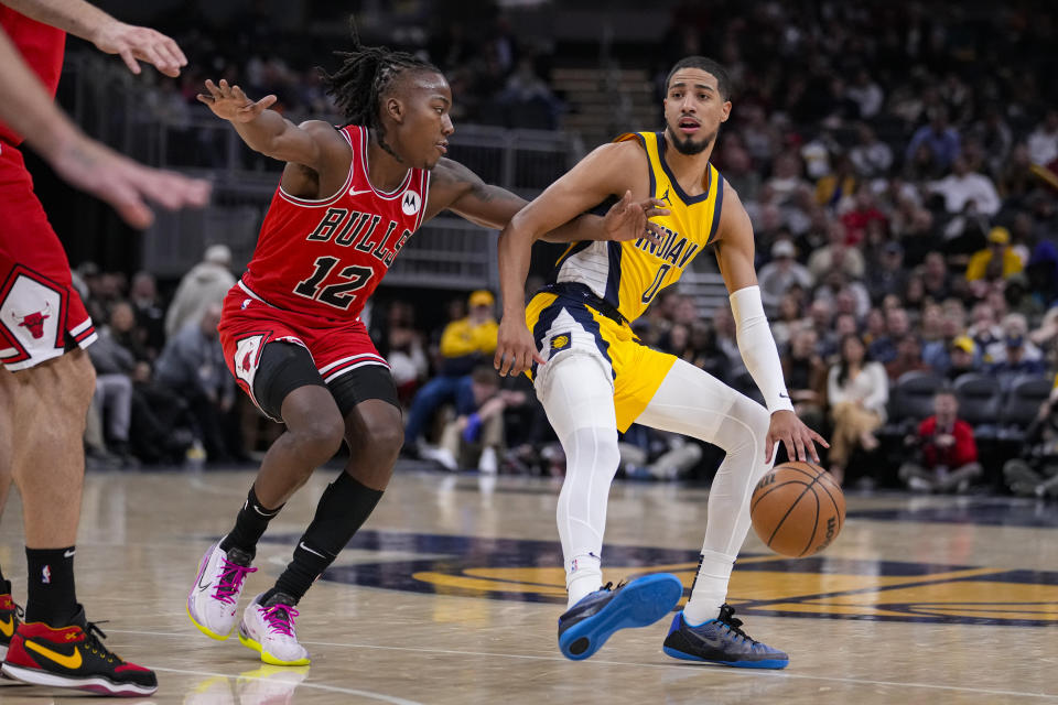 Indiana Pacers guard Tyrese Haliburton (0) drives on Chicago Bulls guard Ayo Dosunmu (12) during the first half of an NBA basketball game in Indianapolis, Monday, Oct. 30, 2023. (AP Photo/Michael Conroy)