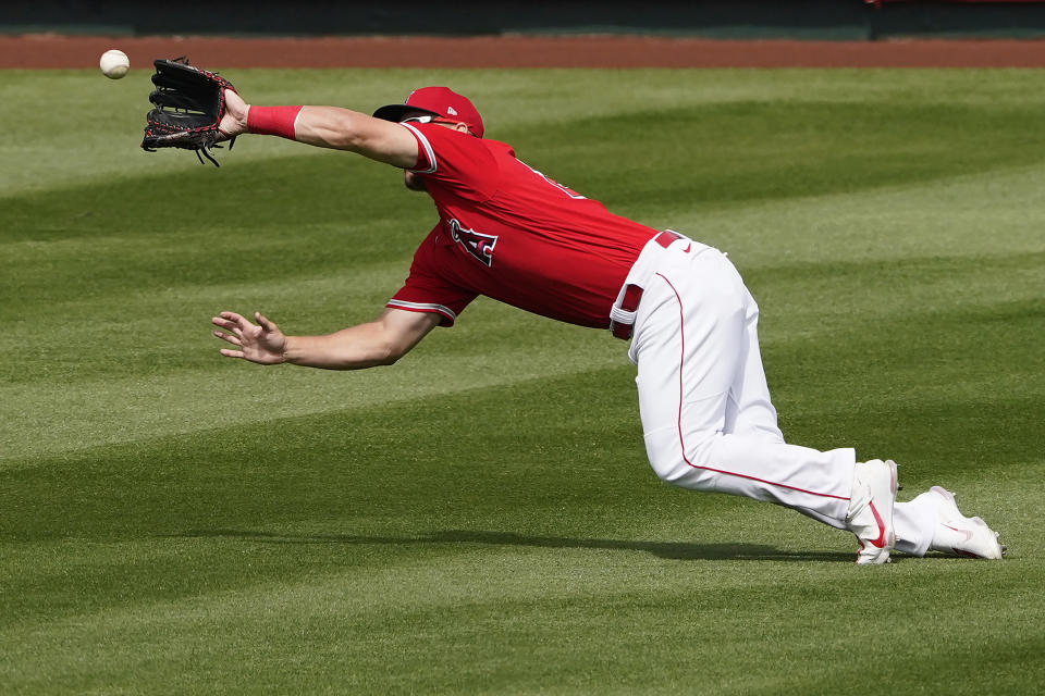 Los Angeles Angels' Mike Trout catches a fly out by Cincinnati Reds' Kyle Holder during the inning of a spring training baseball game, Monday, March 15, 2021, in Tempe, Ariz. (AP Photo/Matt York)