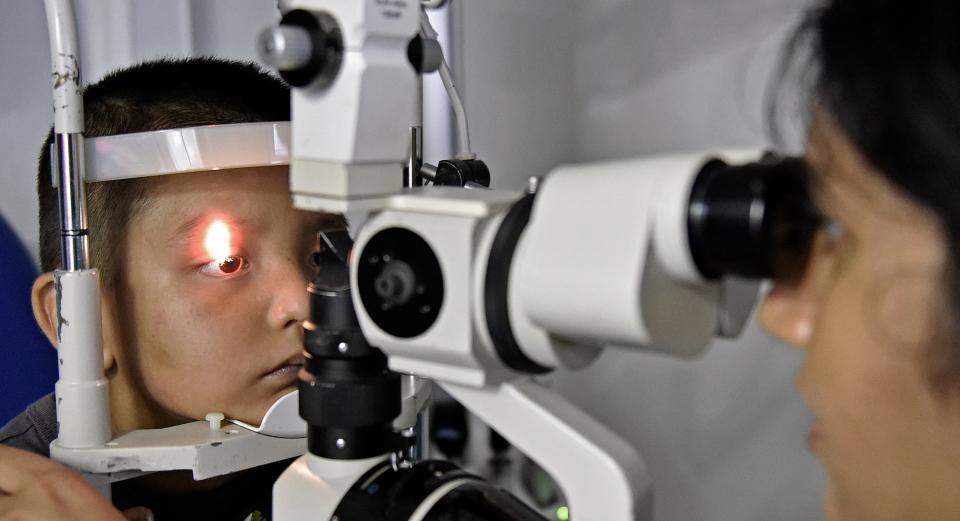 An optometrist gives an eye examination to a young patient.