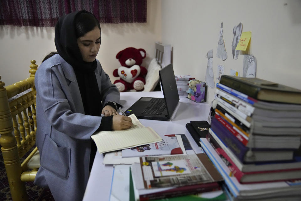 An Afghan university student Bahija Aman, 21, 3rd year anthropology major, takes notes at her home, as she prepares to go back to her university in Kabul, Afghanistan, Thursday, Feb. 24, 2022. Kabul University, among Afghanistan’s oldest and most revered institutions of higher education, reopened Saturday six months after the Taliban retook the country. There were new restrictions in place, however, including gender segregation and mandatory Islamic dress. (AP Photo/Hussein Malla)