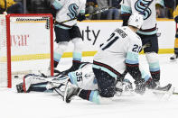 A shot by Nashville Predators left wing Kiefer Sherwood (not shown) gets past Seattle Kraken goaltender Joey Daccord (35) and center Alex Wennberg (21) for a goal during the second period of an NHL hockey game Thursday, March 23, 2023, in Nashville, Tenn. (AP Photo/Mark Zaleski)