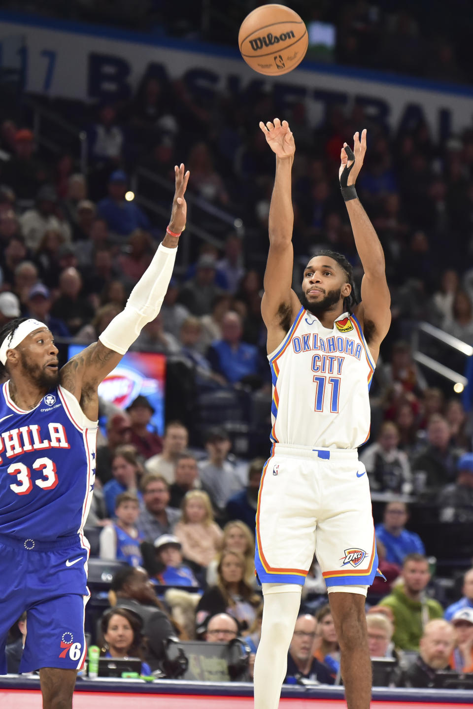 Oklahoma City Thunder guard Isaiah Joe (11) shoots over Philadelphia 76ers forward Robert Covington (33) in the second half of an NBA basketball game Saturday, Nov. 25, 2023, in Oklahoma City. (AP Photo/Kyle Phillips)