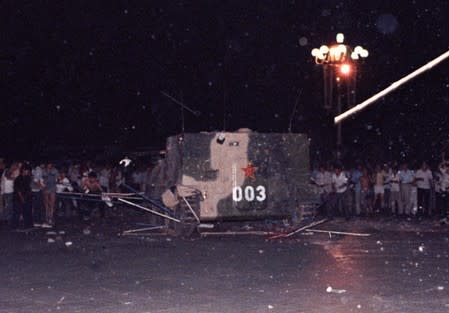 FILE PHOTO: An armoured personnel carrier crushes one of the tents set up on Tiananmen Square by pro-democracy protesters early Sunday morning in Beijing