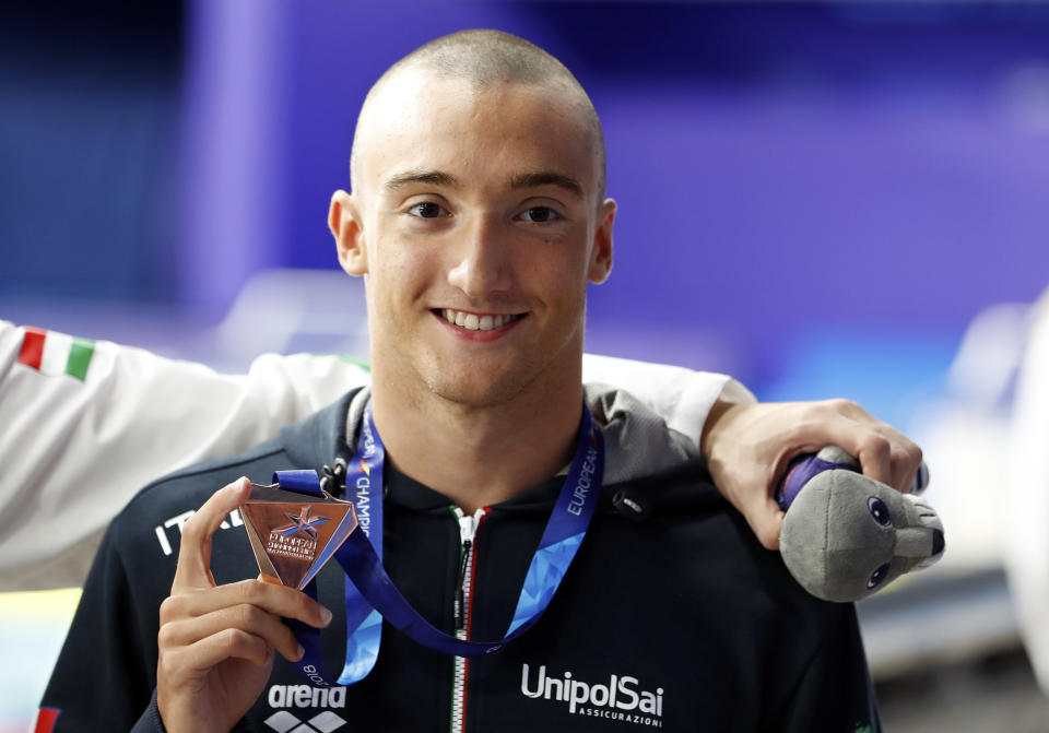 FILE - In this Aug. 5, 2018 file photo, Italy's Federico Burdisso poses with his bronze medal after the 200 meters butterfly men final at the European Swimming Championships in Glasgow, Scotland. A large portion of the Italian swimming team, 13 elite athletes, including Burdisso, has been locked in their tiny hotel rooms at a high-altitude training camp in the Alps for nearly two weeks with the coronavirus. (AP Photo/Darko Bandic, file)