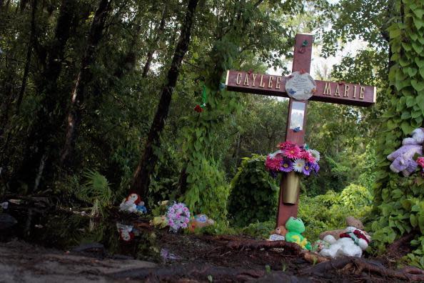 The memorial is covered in dirt and overgrown.