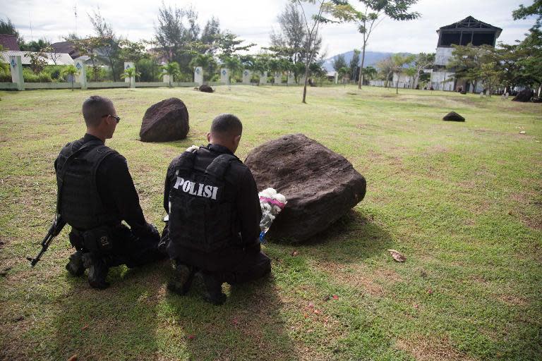 Policemen pray for their dead friends and relatives at a mass grave for victims of the December 26, 2004 tsunami, in Banda Aceh, northern Sumatra, on December 26, 2014