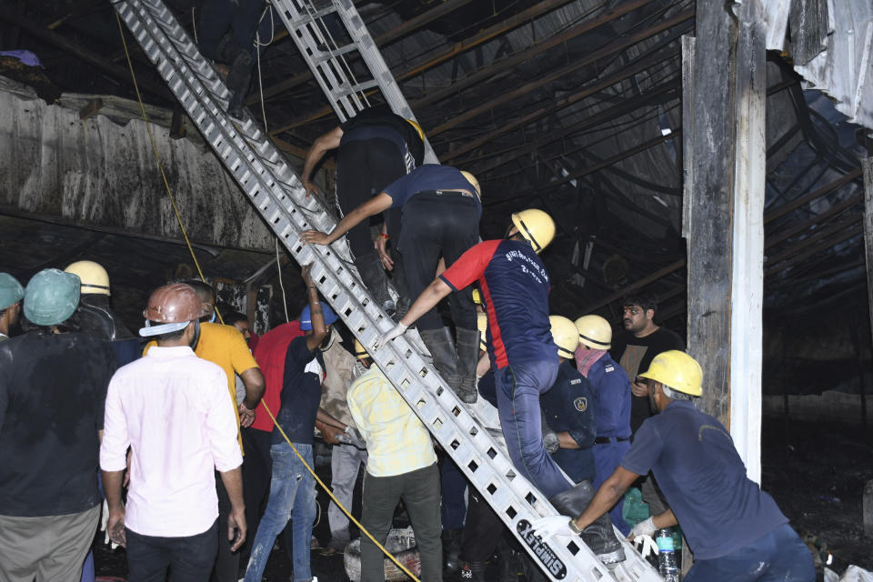 Firefighters and locals douse a fire which broke out in an amusement park, in Rajkot in the Indian state of Gujarat, Saturday, May 25, 2024. A massive fire broke out on Saturday in a fun park in western India, killing more than ten people and injuring some others, news reports said. (AP Photo/Chirag Chotaliya)