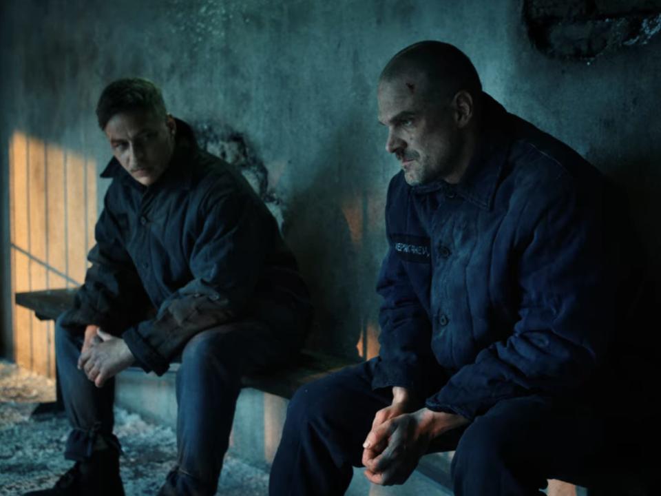 Two men sitting in a dark prison cell.