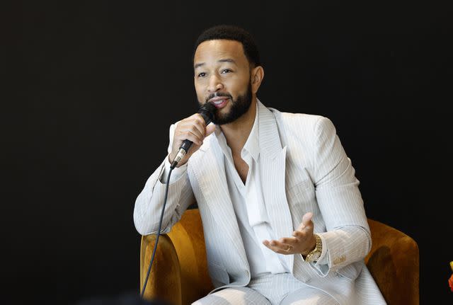 <p>Frazer Harrison/Getty</p> John Legend speaks on stage at The Voices of Beauty Summit on March 27, 2024