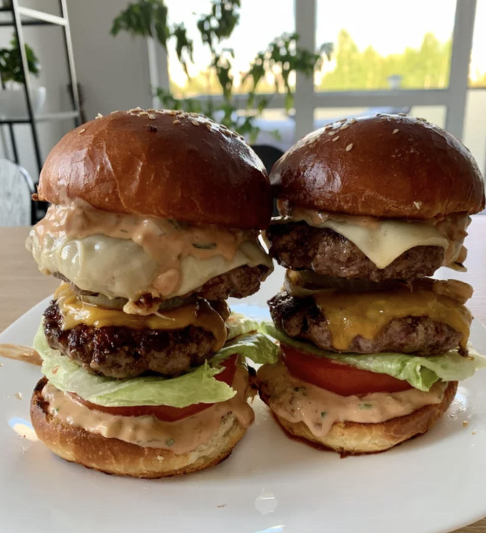 Two very tall hamburgers sit side-by-side