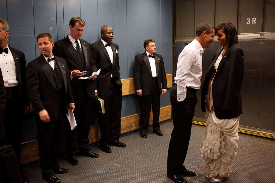 Barack and Michelle Obama share a moment, surrounded by aides, in a backstage elevator's casual setting