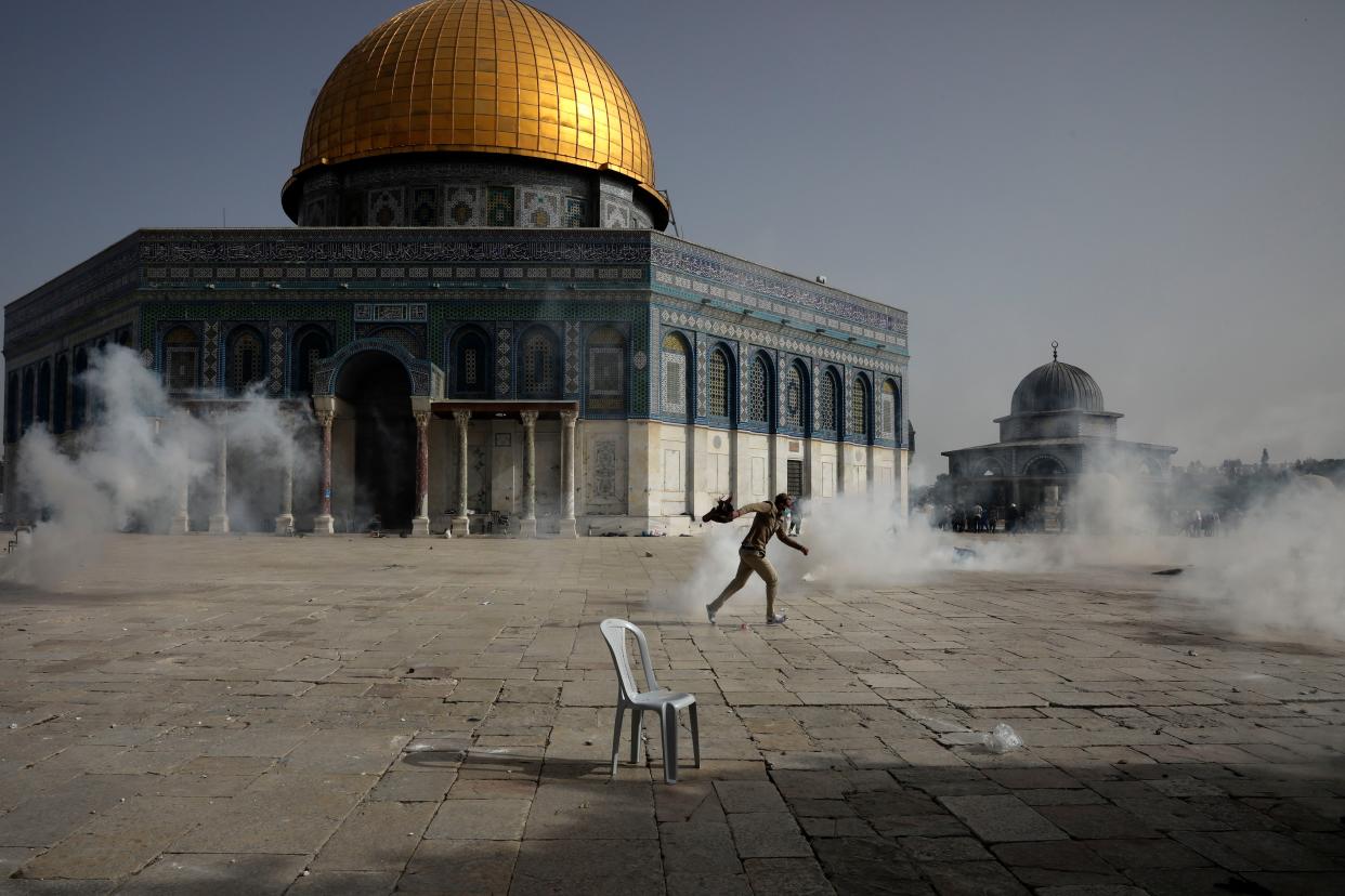 A Palestinian man runs away from tear gas during clashes with Israeli security forces in front of the Dome of the Rock Mosque at the Al-Aqsa Mosque compound in Jerusalem's Old City Monday, May 10, 2021.