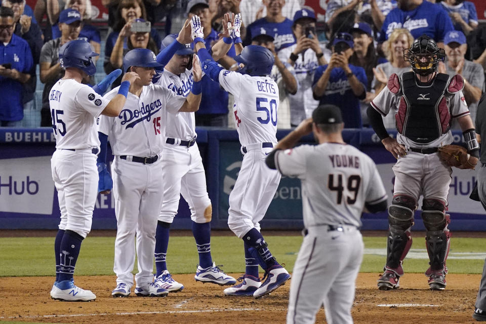 Los Angeles Dodgers' Mookie Betts, third from right, is congratulated by Matt Beaty, left, Austin Barnes, second from left, and AJ Pollock, third from left, after hitting a grand slam as Arizona Diamondbacks starting pitcher Alex Young, second from right, watches along with catcher Bryan Holaday during the seventh inning of a baseball game Saturday, July 10, 2021, in Los Angeles. (AP Photo/Mark J. Terrill)