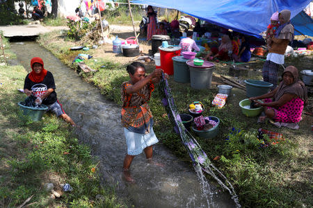 Villagers affected by an earthquake clean their clothes near their makeshift tents in Petobo neighbourhood in Palu, Indonesia, October 6, 2018. REUTERS/Athit Perawongmetha