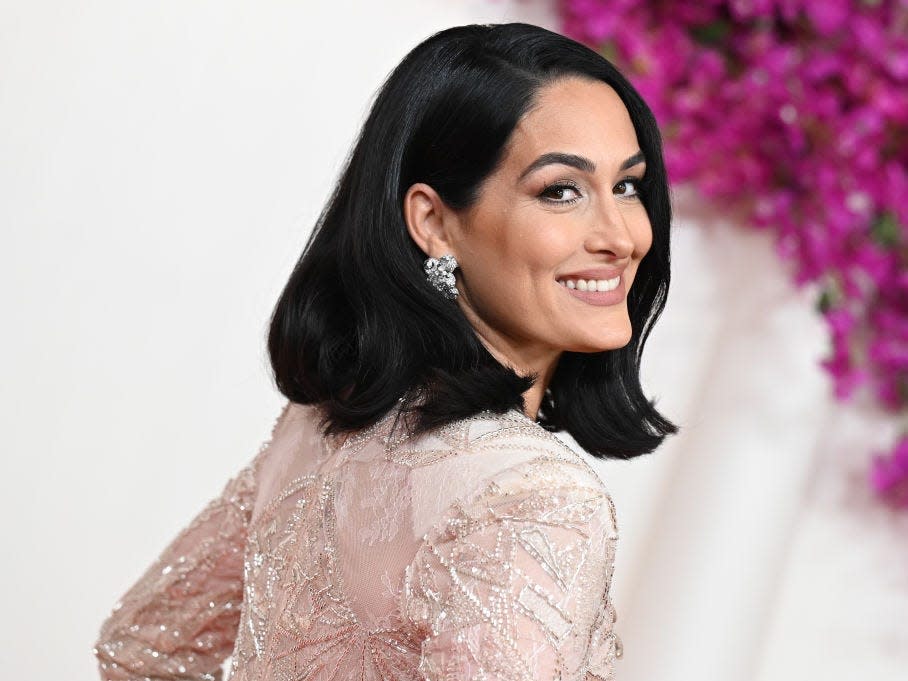 Nikki Bella, a woman with black hair posing on a red carpet