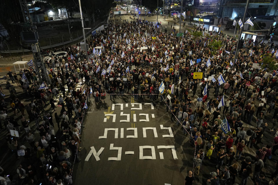 People gather next to a sign displayed on the street that reads in Hebrew "Rafah can wait, they cannot", in reference of a possible Israeli offensive on the Rafah, city in southern Gaza Strip, and calling for the release of the Israeli hostages held by the Hamas militant group, during a protest in Tel Aviv, Monday, April 29, 2024. (AP Photo/Ohad Zwigenberg)