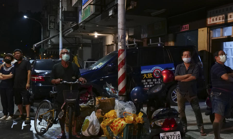 Residents look on, after a building fire, in Kaohsiung, southern Taiwan, Thursday, Oct. 14, 2021. Officials say at least 46 people were killed and over 40 injured after a fire broke out in a decades-old mixed commercial and residential building in the Taiwanese port city of Kaohsiunging. Neighborhood residents say the 13-story building was home to many poor, elderly and disabled people and it wasn’t clear how many of the 120 units were occupied. (AP Photo/Huizhong Wu)