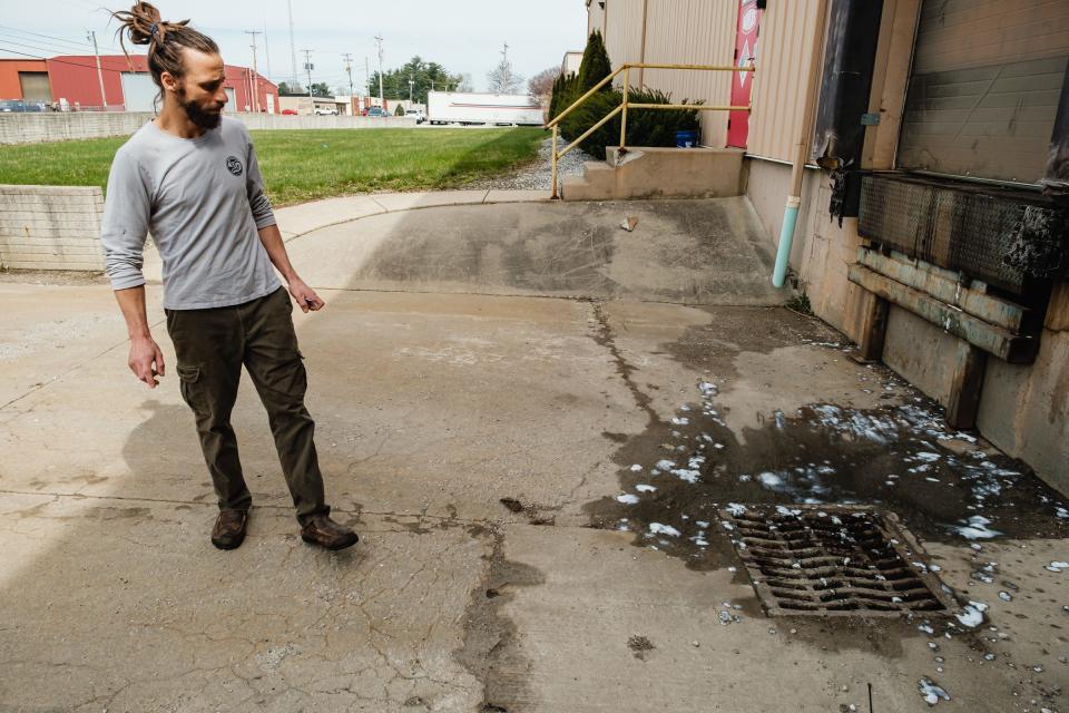 New Philadelphia-area resident Bradley Schilling looks over a chemical substance that had apparently been dumped on Monday into a drain at Hawkins Water Treatment, 1161 Commercial Ave. SE, New Philadelphia, and subsequently flowed into the Tuscarawas River near the home he rents.