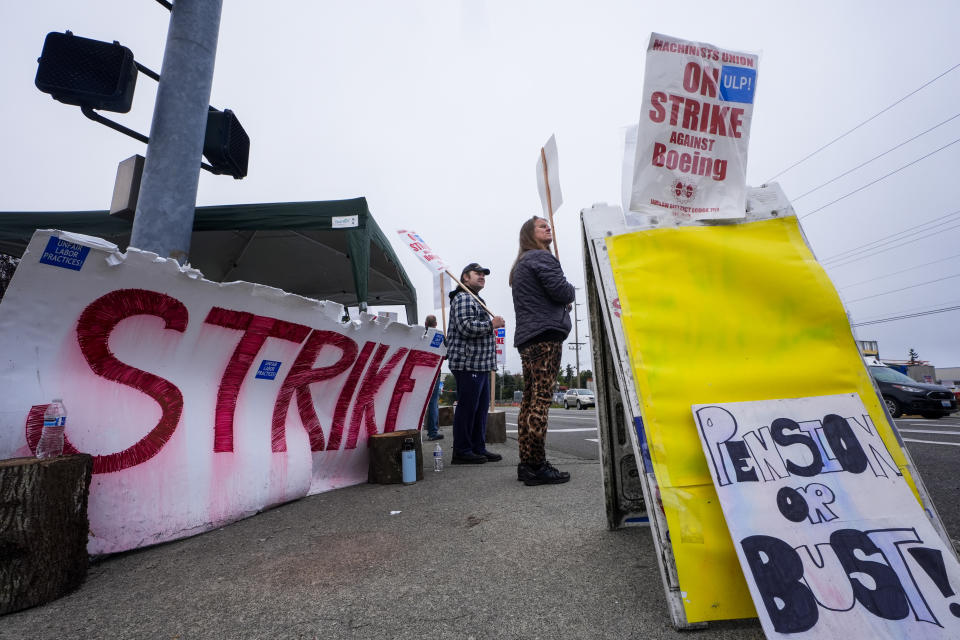 Denise Strike, a 13-year employee of Boeing, right, waves picket signs with 10-year employee Jacob Larson, left, as they strike after union members voted to reject a contract offer, Sunday, Sept. 15, 2024, near the company's factory in Everett, Wash. (AP Photo/Lindsey Wasson)