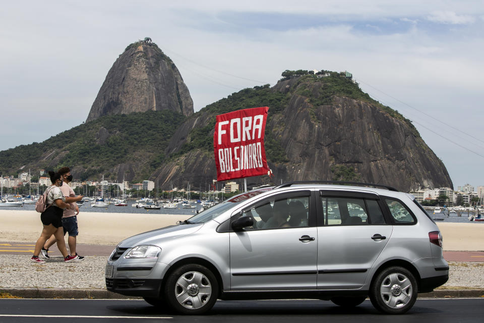 People hold a sign that reads "Bolsonaro out," during a protest against the government's response in combating COVID-19 and demanding the impeachment of Brazilian President Jair Bolsonaro, backdropped by the Sugar Loaf mountain in Rio de Janeiro, Brazil, Sunday, Jan. 31, 2021. (AP Photo/Bruna Prado)