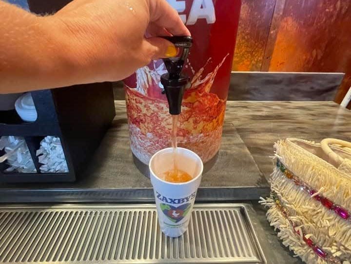 The writer dispenses sweet tea into a cup at Zaxby's