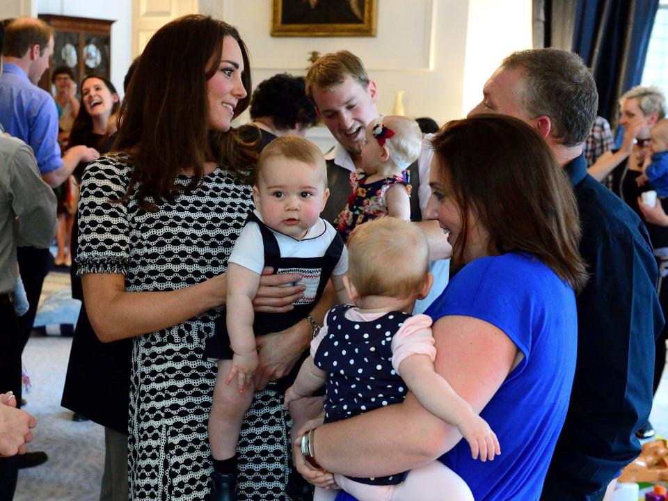 Kate Middleton holds Prince George and talks to other moms in 2014.