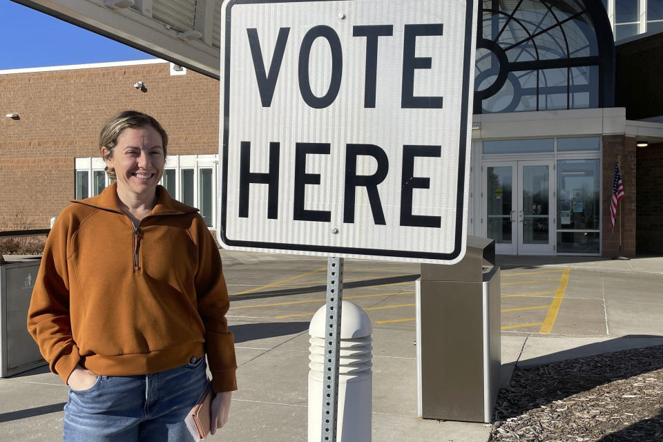 Molly Menton, 40, stands next to a "Vote Here" sign outside the Eden Prairie Library polling place in Eden Prairie, Minn., on Tuesday, March 5, 2024. Menton, who identifies as a lifelong Democrat in the Twin Cities suburb, said she voted for Joe Biden in the primary election. (AP Photo/Trisha Ahmed)