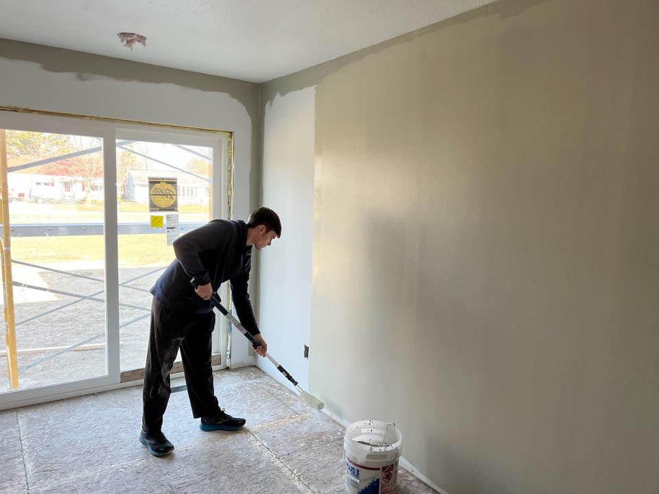 Monroe High School student Christian Lombardo paints the kitchen of the Trojan Build 4 project on Charles Street in Monroe.