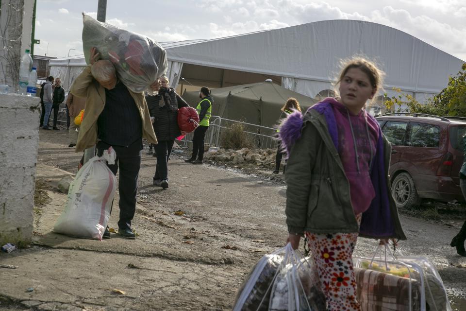 People carry clothes and other supplies distributed by authorities in Thumane, western Albania, Friday, Nov. 29, 2019. The operation to find survivors and recover bodies from Albania's deadly earthquake was winding down Friday as the death toll climbed to 49. (AP Photo/Visar Kryeziu)