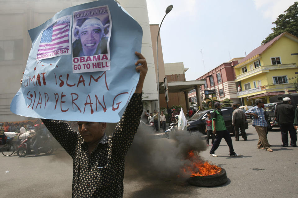An Indonesian Muslim holds up a poster as a tire burns during a protest against an American film that ridicules Prophet Muhammad outside the U.S. Consulate in Medan, North Sumatra, Indonesia, Tuesday, Sept. 18, 2012. Indonesians continue to protest the anti-Islam film "Innocence of Muslims," torching the flag and tires outside the consulate in the country's third largest city of Medan. The poster reads: "Muslims are ready for war."(AP Photo/Binsar Bakkara)