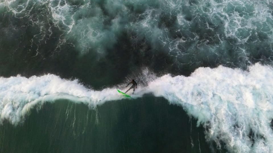 An aerial view of a surfer surfing among the giant waves of Atlantic Ocean in Dakar, Senegal on May 25, 2024. In Senegal, which has 724 kilometres of coastline, surf schools with large and small beaches along the coastline are flooded by surfing enthusiasts. Surfers gather at the beach at noon enjoy the sea until the evening hours as the waves grow.