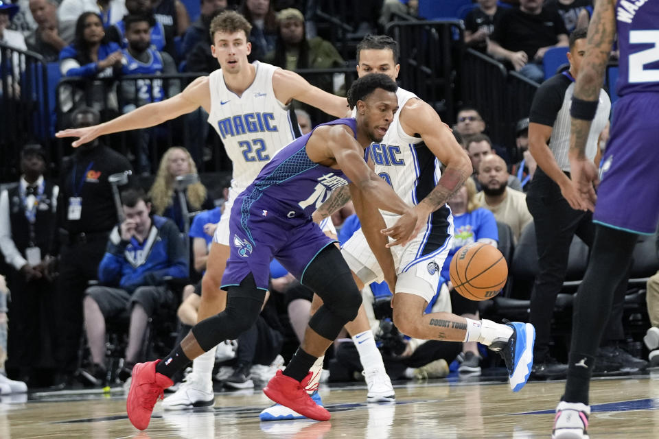 Charlotte Hornets guard Ish Smith, center, goes after a loose ball in front of Orlando Magic forward Franz Wagner (22) and guard Cole Anthony, right, during the first half of an NBA basketball game, Sunday, Nov. 26, 2023, in Orlando, Fla. (AP Photo/John Raoux)