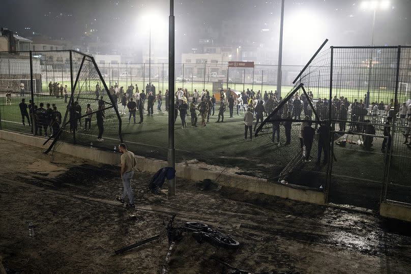 Los vecinos se reúnen en el campo de fútbol en los Altos del Golán que fue alcanzado por un cohete el sábado 27 de julio