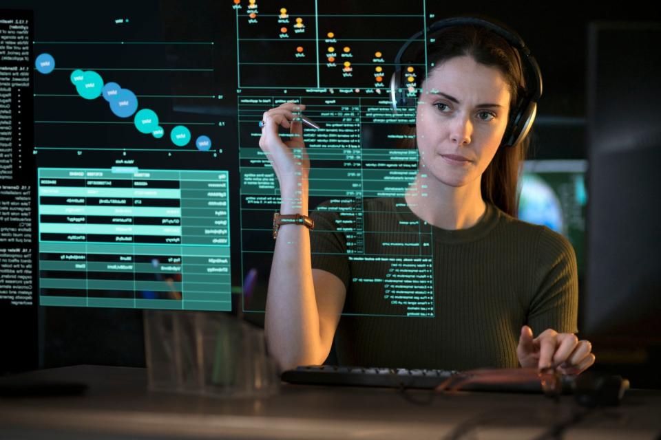 A person looking at graphs and data on a see-though computer display.