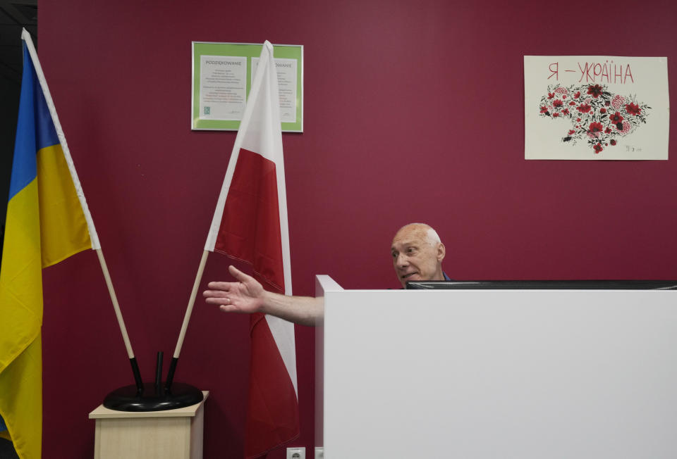 A teacher sitting at a reception desk gestures at a school run by the Unbreakable Ukraine foundation in Warsaw, Poland, Saturday June 3, 2023. Russian forces have destroyed 262 educational institutions and damaged another 3,019 in their invasion of Ukraine, according to government figures. For those who've fled to other countries, schooling is suffering in unprecedented ways, according to families, educators, experts and advocates. The effects of war and relocation combined with the challenges of studying in a new country are compounding educational setbacks for young refugees. (AP Photo/Czarek Sokolowski)