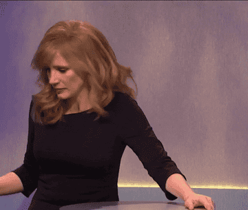 A GIF of Jessica Chastain uncorking a wine bottle with her teeth before taking a big slug of it