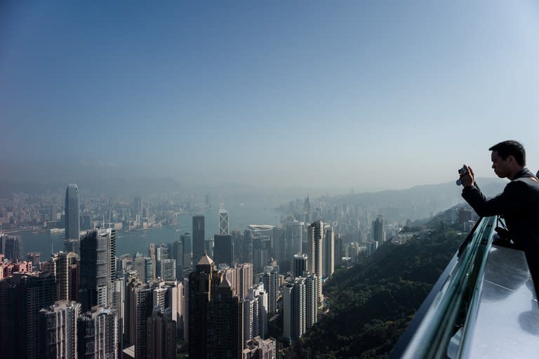 A tourist takes pictures of the Hong Kong skyline on Friday. Tens of thousands have taken to the streets in recent months in marches against Chief Executive Leung Chun-ying, who took over from Donald Tsang last July after being elected by a 1,200-strong pro-Beijing committee