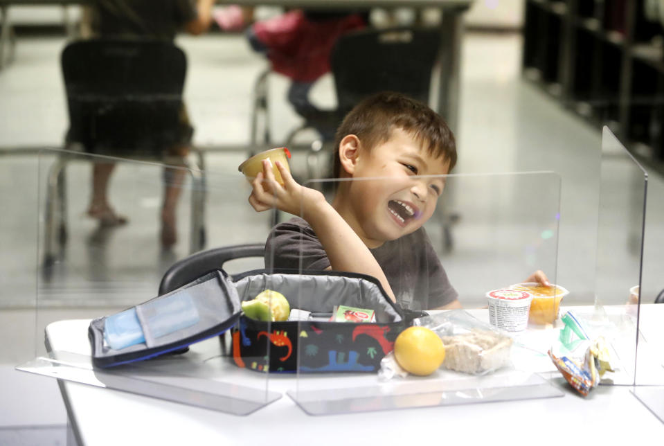 Bruce McCall, 5, laughs as he eats his lunch behind plastic barriers during martial arts daycare summer camp at Legendary Blackbelt Academy in Richardson, Texas, Tuesday, May 19, 2020. As daycare and youth camps re-open in Texas, operators are following appropriate safety measure to insure kids stay safe from COVID-19. (AP Photo/LM Otero)