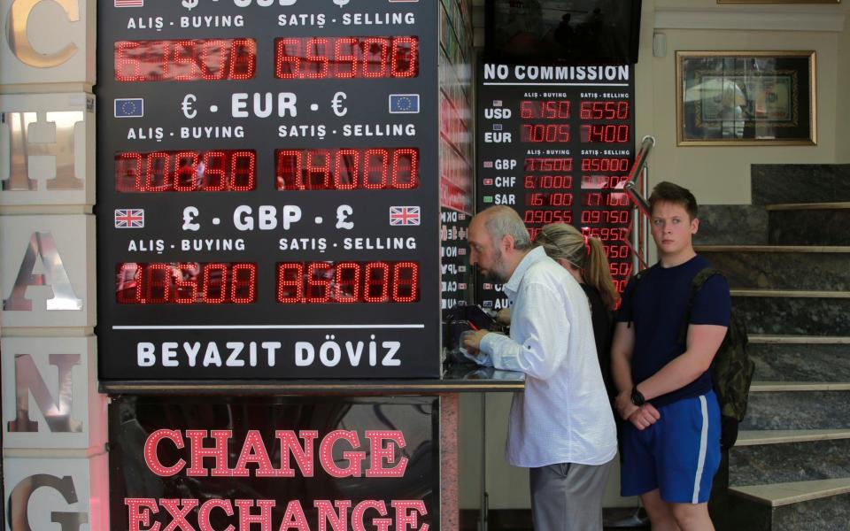 People queue at a foreign currency exchange shop in Istanbul - AP