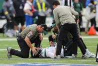 A trainer checks on New York Jets quarterback Zach Wilson after he suffered a knee injury during the first half of an NFL football game against the Buffalo Bills, Sunday, Nov. 6, 2022, in East Rutherford, N.J. (AP Photo/Noah K. Murray)