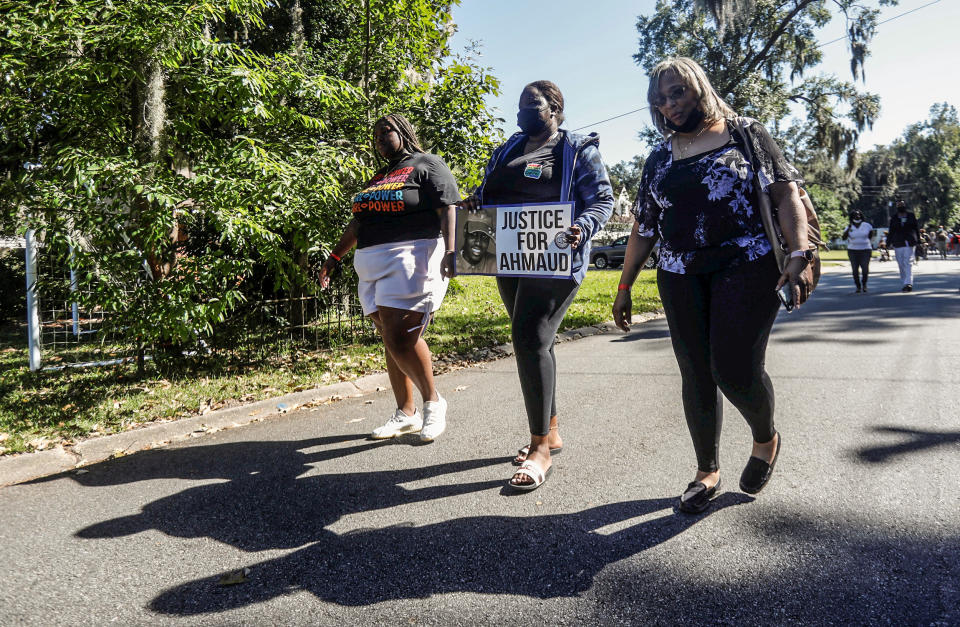 A woman holds a placard as people visit Satilla Shores neighborhood, where Ahmaud Arbery was killed, as the jury selection continues in Arbery's murder trial, in Brunswick, Ga., on Oct. 19, 2021. (Octavio Jones / Reuters)