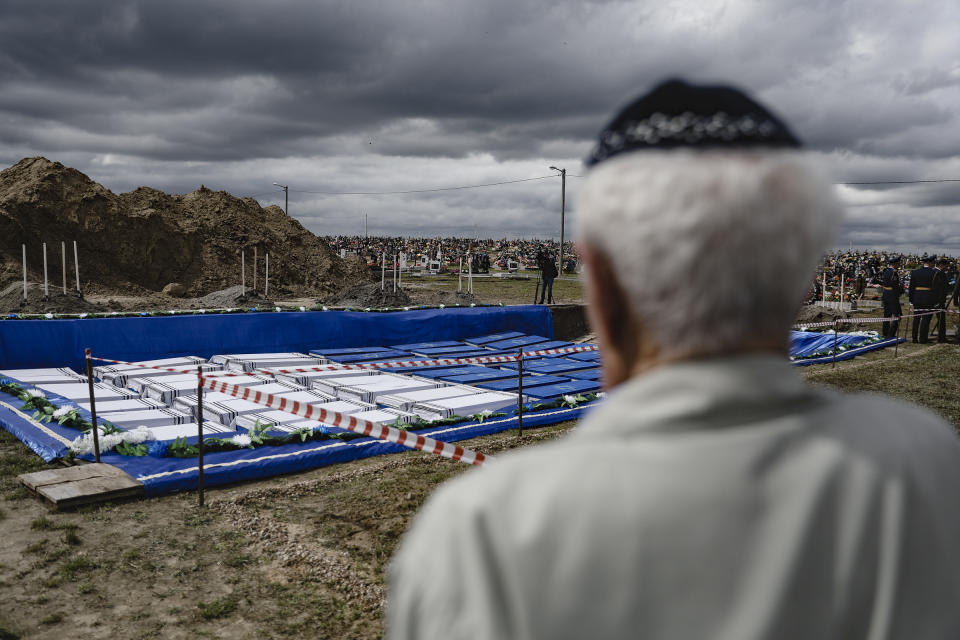 A man looks at coffins before burying the remains of Holocaust victims at a cemetery just outside Brest, Belarus, Wednesday, May 22, 2019. Remains of more than 1,000 Holocaust victims were laid to rest on Wednesday in a Belarusian city on the border with Poland after a mass grave was discovered on a building site earlier this year. (Uladz Hrydzin, Radio Free Europe/Radio Liberty via AP)