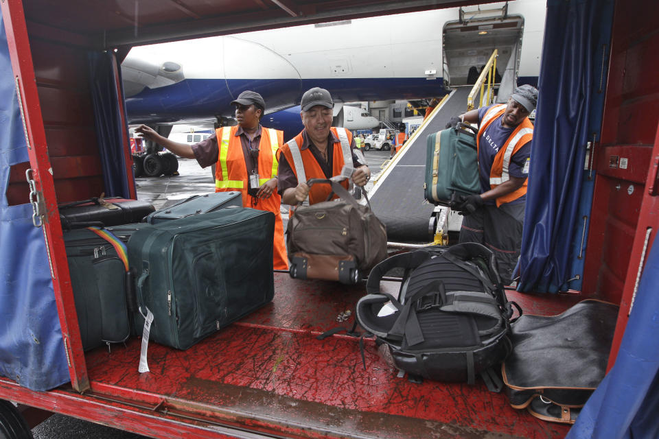 In this Wednesday, Aug. 1 2012 photo, Delta Air Lines ramp agents unload bags from a flight arriving at JFK International airport in New York. Travelers still have to put up with packed planes, rising fees and unpredictable security lines, but they are missing fewer business meetings or chances to tuck their kids into bed. Nearly 84 percent of domestic flights arrived within 15 minutes of their schedule time in the first half of the year, the best performance since the government started tracking such data in 1988. (AP Photo/Mary Altaffer)